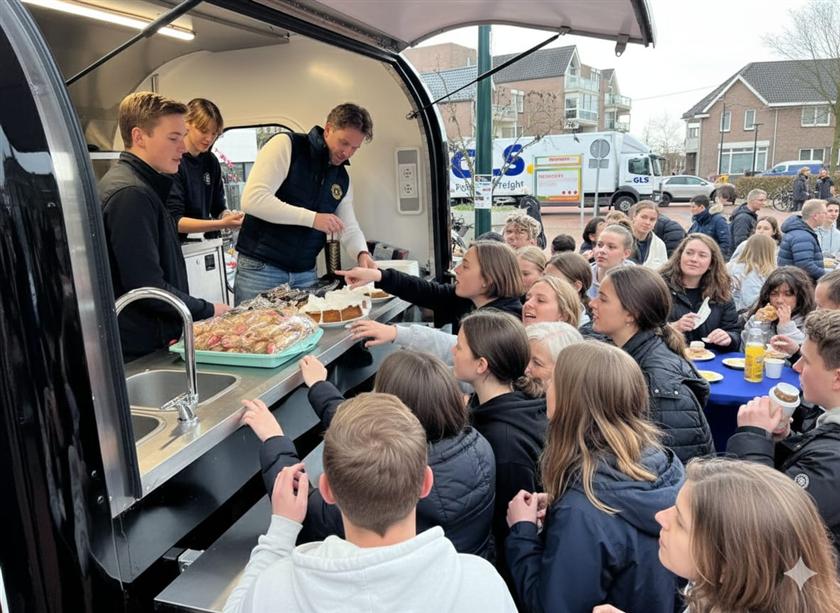 Taartverkoop vanuit de foodtruck, met bezoekers voor de toonbank